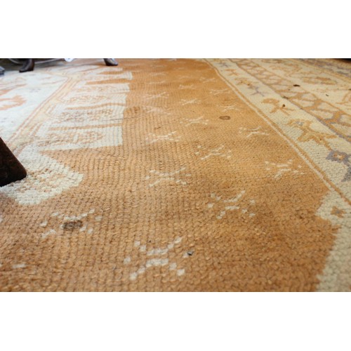 389 - A large Turkish wool carpet, in orange and cream colourways with a larger central medallion, 406cm x... 