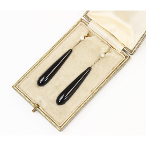 117 - A pair of early 20th century black onyx and pearl earrings, each designed as a tapered black onyx ba... 