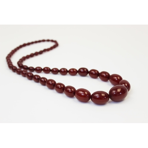 128 - A cherry amber bead necklace, comprising fifty-seven polished oval beads measuring between 8mm x 6mm... 