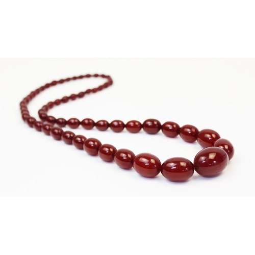 128 - A cherry amber bead necklace, comprising fifty-seven polished oval beads measuring between 8mm x 6mm... 