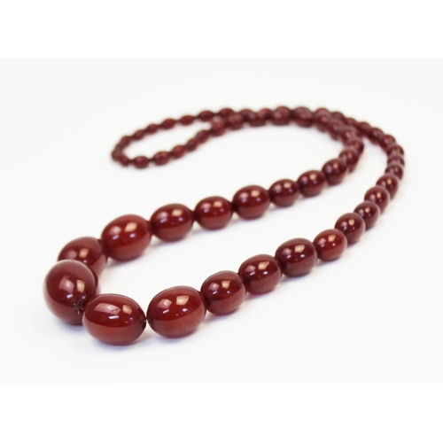 128 - A cherry amber bead necklace, comprising fifty-seven polished oval beads measuring between 8mm x 6mm... 