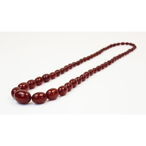 128 - A cherry amber bead necklace, comprising fifty-seven polished oval beads measuring between 8mm x 6mm... 