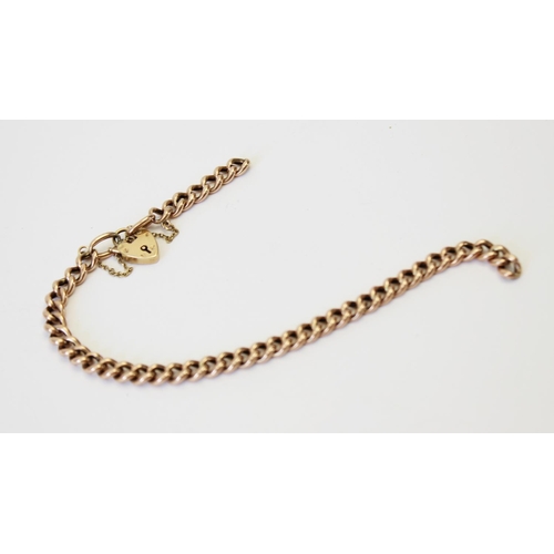 131 - A yellow metal curb link bracelet, 21.5cm long, suspending a 9ct gold heart-shaped padlock fastener,... 