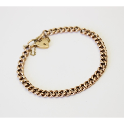 131 - A yellow metal curb link bracelet, 21.5cm long, suspending a 9ct gold heart-shaped padlock fastener,... 