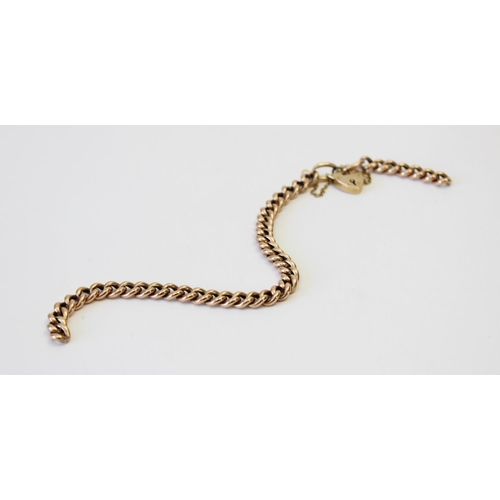 131 - A yellow metal curb link bracelet, 21.5cm long, suspending a 9ct gold heart-shaped padlock fastener,... 