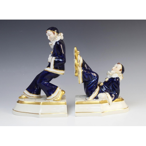 506 - A pair of Royal Dux Pierrot bookends, one modelled leaning, the other with his feet in the air, each... 