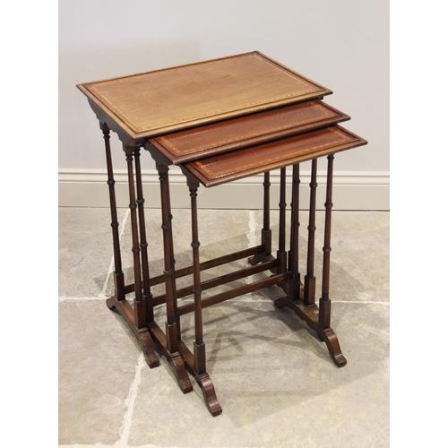 871 - An Edwardian nest of three mahogany and satinwood cross banded tea tables, upon slender ring turned ... 