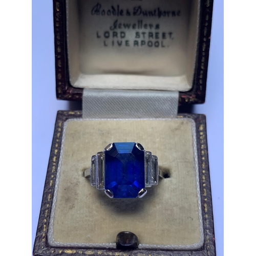 186 - An Art Deco sapphire and diamond ring, the central octagonal step cut sapphire (measuring 11.79mm L ... 