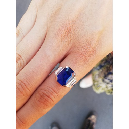 186 - An Art Deco sapphire and diamond ring, the central octagonal step cut sapphire (measuring 11.79mm L ... 