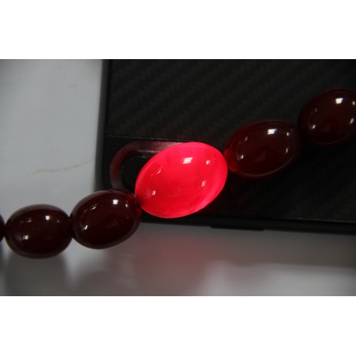 128 - A cherry amber bead necklace, comprising fifty-seven polished oval beads measuring between 8mm x 6mm... 