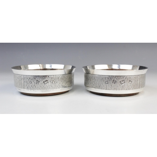 132 - A pair of silver mounted bottle coasters by P H Vogel & Co, Birmingham 1973, each of circular form w... 