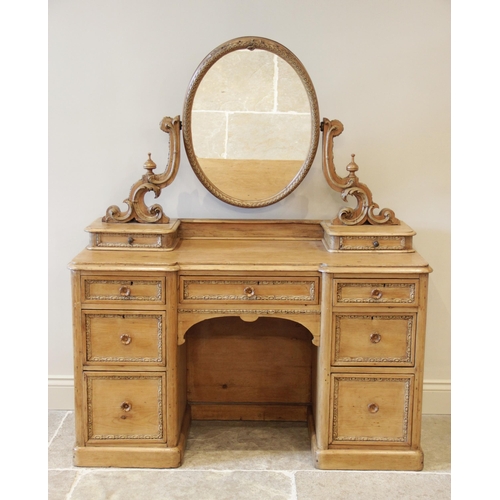 891 - A Victorian pine inverted breakfront kneehole dressing table, the oval swing mirror raised upon 'C' ... 