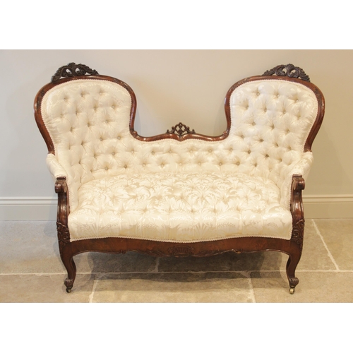 904 - A Victorian mahogany framed double spoon back sofa, the shaped button back applied with carved leafy... 