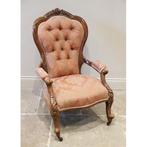 910 - A late Victorian carved walnut button back salon chair, the waisted button back with a foliate carve... 