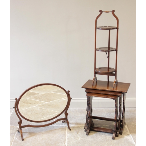 919 - An early 20th century oak nest of three tea tables, each with a rectangular top raised upon lyre sha... 