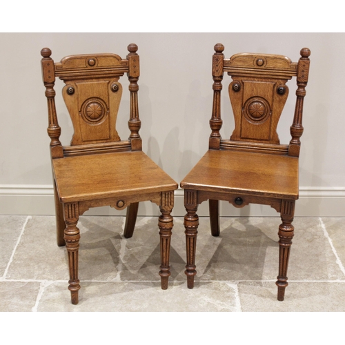 611 - A pair of Victorian Aesthetic Movement honey oak hall chairs, each chair with button finials above a... 