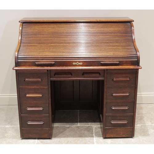 644 - An early 20th century oak roll top desk, the tambour front opening to a compartmentalised interior o... 