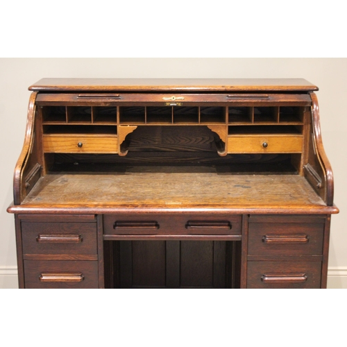 644 - An early 20th century oak roll top desk, the tambour front opening to a compartmentalised interior o... 