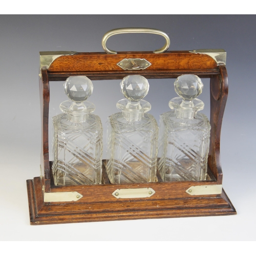 83 - A three bottle tantalus, comprising; three cut glass decanters, each approx. 23cm high, all set to a... 