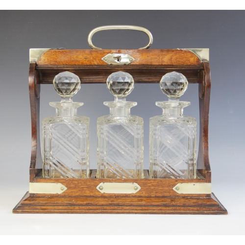 83 - A three bottle tantalus, comprising; three cut glass decanters, each approx. 23cm high, all set to a... 