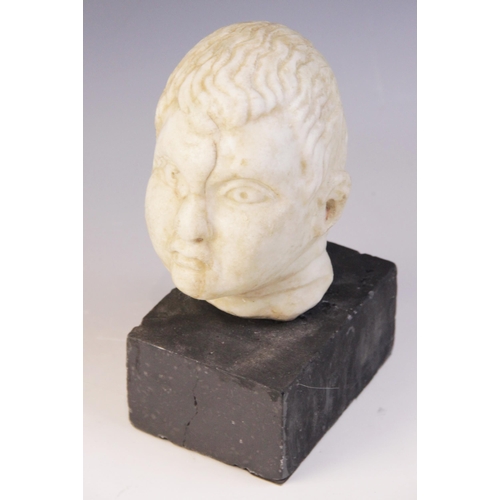 103 - A carved marble head, depicting a young boy with distinctive hair details, 15m high, upon a plinth b... 