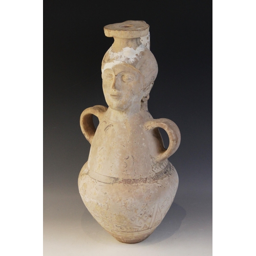 108 - A terracotta water jug, the amphora form jug with loop handles, the neck modelled as a head with fla... 