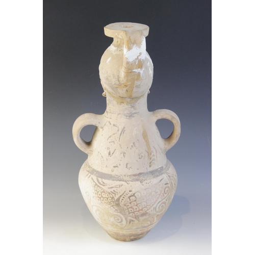 108 - A terracotta water jug, the amphora form jug with loop handles, the neck modelled as a head with fla... 