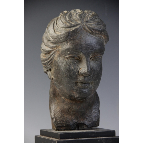 165 - A carved stone female head, the dark coloured stone carving (possibly originally part of a larger gr... 