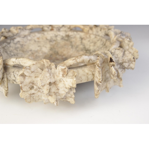 172 - A figured alabaster dish in the Grand Tour manner, the rim modelled as a pierced and relief carved g... 