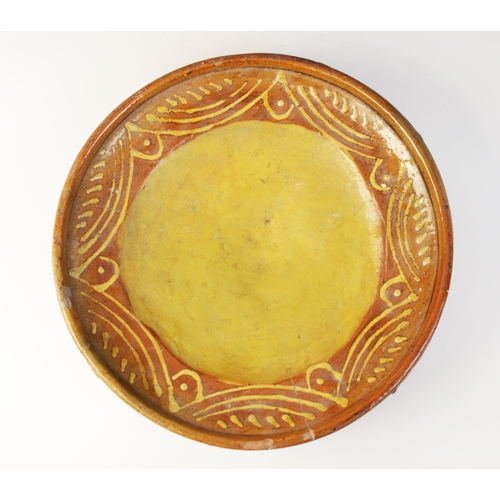 289 - A terracotta slipware footed dish, of circular form with three blade feet to base, the raised rim ab... 