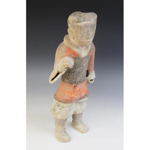 321 - A Chinese pottery warrior, possibly Han dynasty, modelled standing wearing armour and painted in bla... 