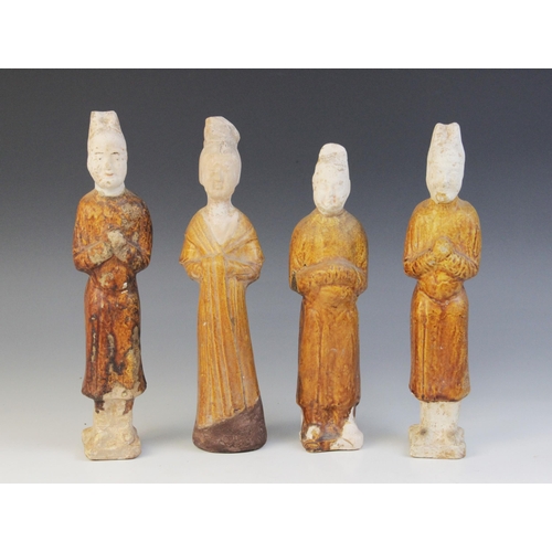 327 - Four Chinese pottery amber glazed figures, possibly Tang dynasty, each modelled standing and with th... 