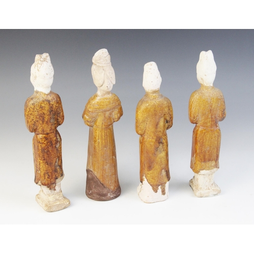 327 - Four Chinese pottery amber glazed figures, possibly Tang dynasty, each modelled standing and with th... 