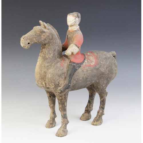 334 - A Chinese pottery model of a figure riding a horse, possibly Han dynasty, the horse standing on four... 