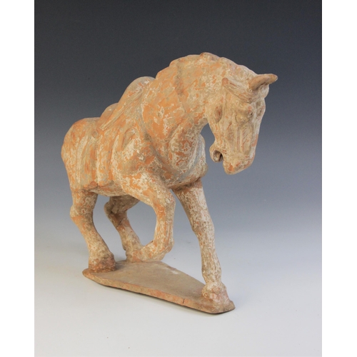 337 - A Chinese pottery model of a horse, possibly Tang dynasty, modelled with one leg raised, with saddle... 