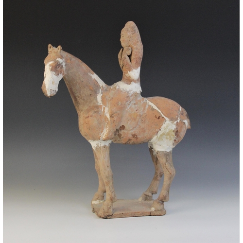 338 - A Chinese pottery model of a figure riding a horse, possibly Tang dynasty, the horse raised on four ... 