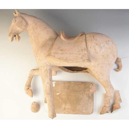 341 - A large Chinese pottery model of a horse, possibly Tang dynasty, modelled on four legs, with one rai... 