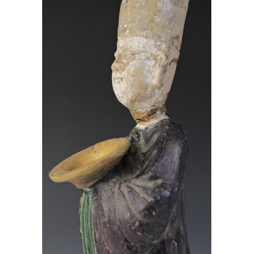 343 - A large Chinese Sancai glazed attendant, possibly Tang dynasty, modelled standing holding an offerin... 