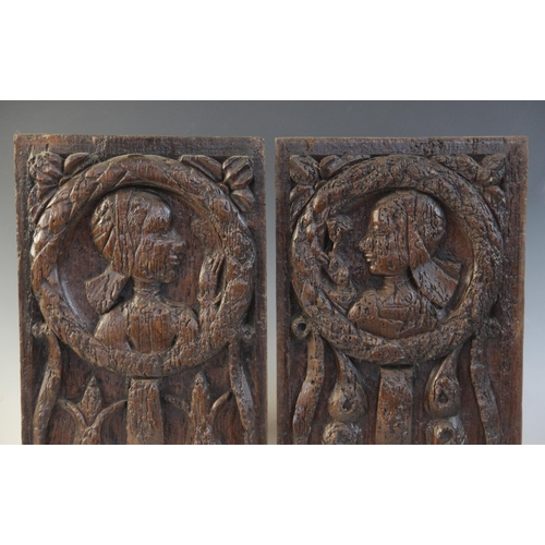 412 - A pair of oak Romayne type panels, each designed with a female holding a single flower within a laur... 