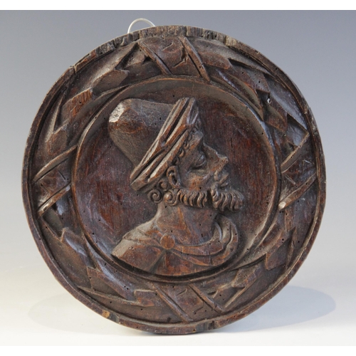 413 - A 16th century oak carved circular panel, circa 1550, depicting a bearded male wearing a hat in a la... 