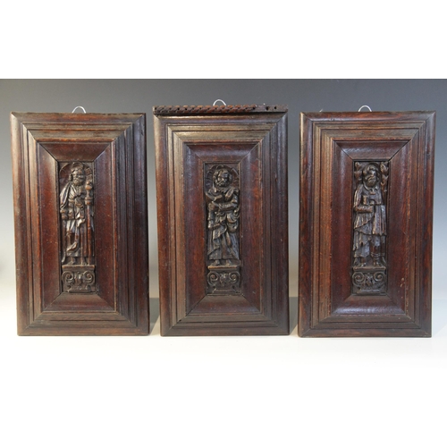 419 - Three carved oak Flemish panels of saints, circa 1600, each Saint carved standing upon a scroll plin... 