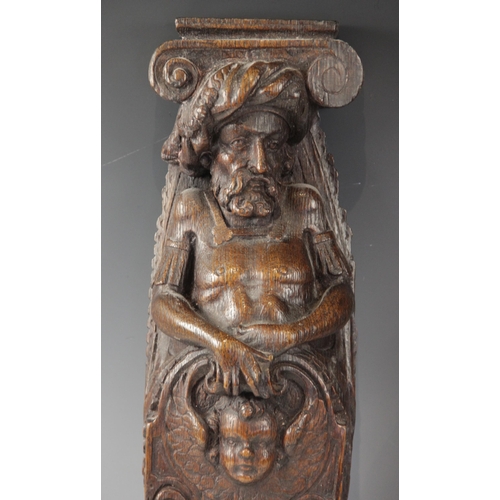 436 - A pair of 17th century oak figural terms, Flemish, each carved with a male bust wearing a hat above ... 