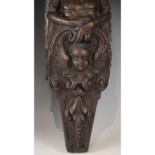 436 - A pair of 17th century oak figural terms, Flemish, each carved with a male bust wearing a hat above ... 