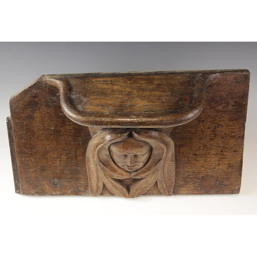 437 - A late 15th century carved oak misericord, carved with a central green man below the seat, 48cm high... 