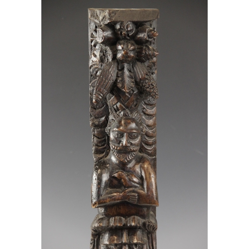 438 - An early 17th century carved walnut term, circa 1630, carved with a male holding a bird, atop a lion... 