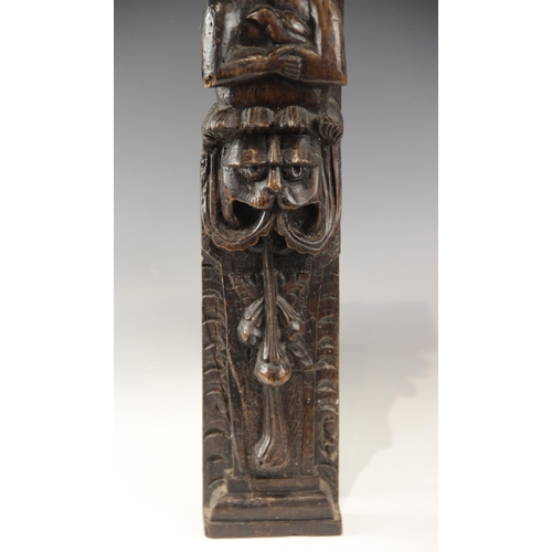 438 - An early 17th century carved walnut term, circa 1630, carved with a male holding a bird, atop a lion... 