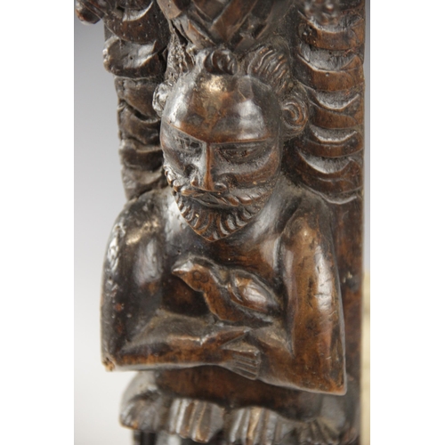 438 - An early 17th century carved walnut term, circa 1630, carved with a male holding a bird, atop a lion... 