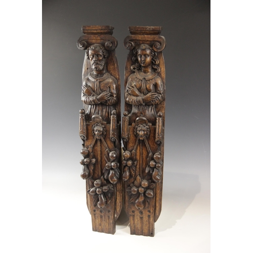 440 - A pair of 17th century carved oak figural terms, Flemish, one male, the other female, both with fold... 