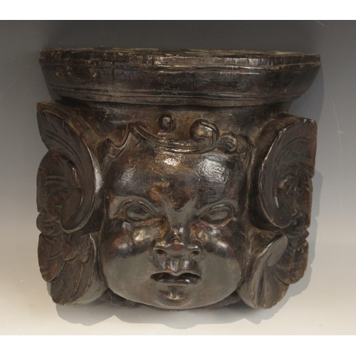 444 - A baroque carved corbel, designed with a cherub mask, flanked by scrolls, 30cm high x 32.5cm wide