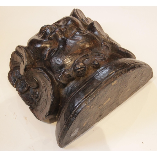 444 - A baroque carved corbel, designed with a cherub mask, flanked by scrolls, 30cm high x 32.5cm wide